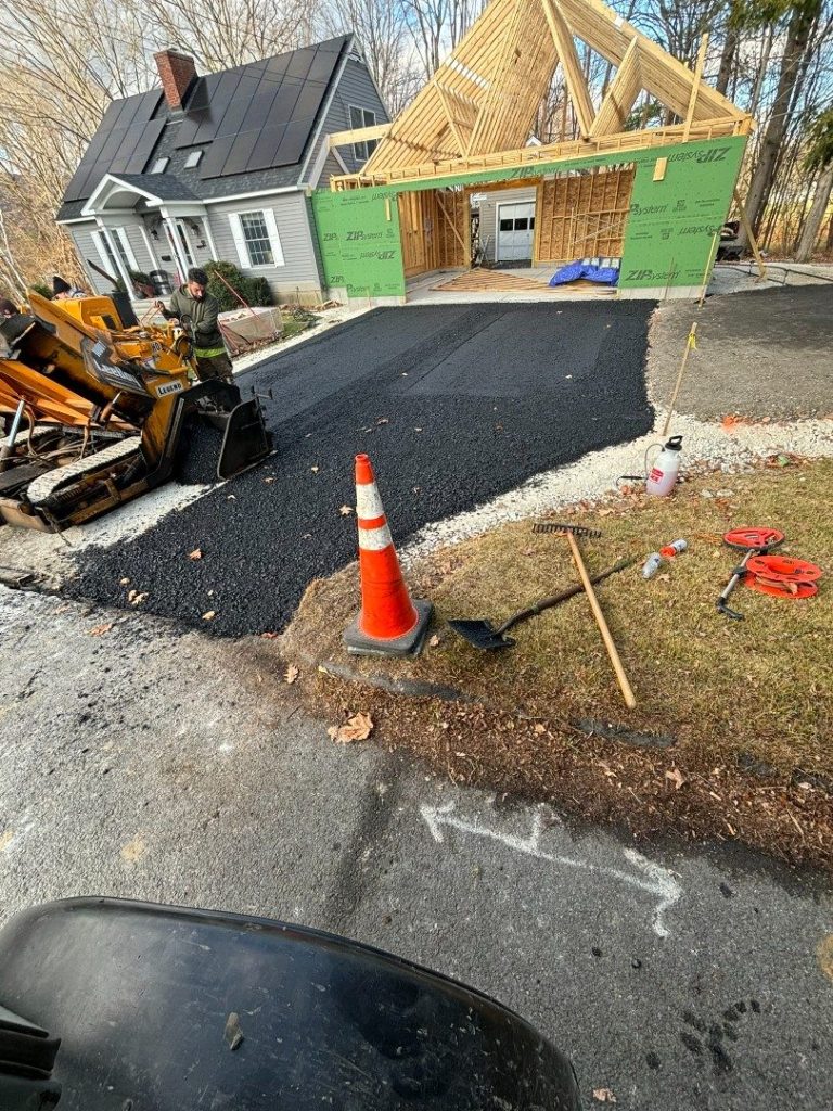 Asphalt being laid at a new-construction home with a compact loader
