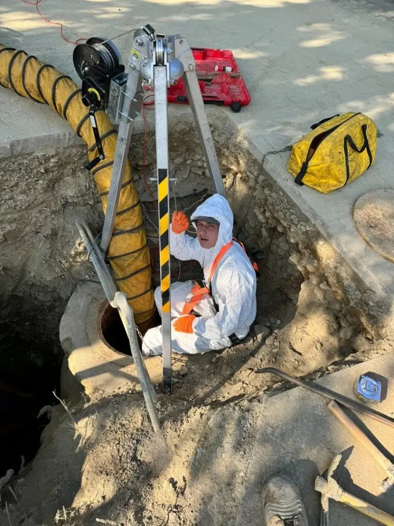 A1 technician in protective gear working inside a sewer manhole
